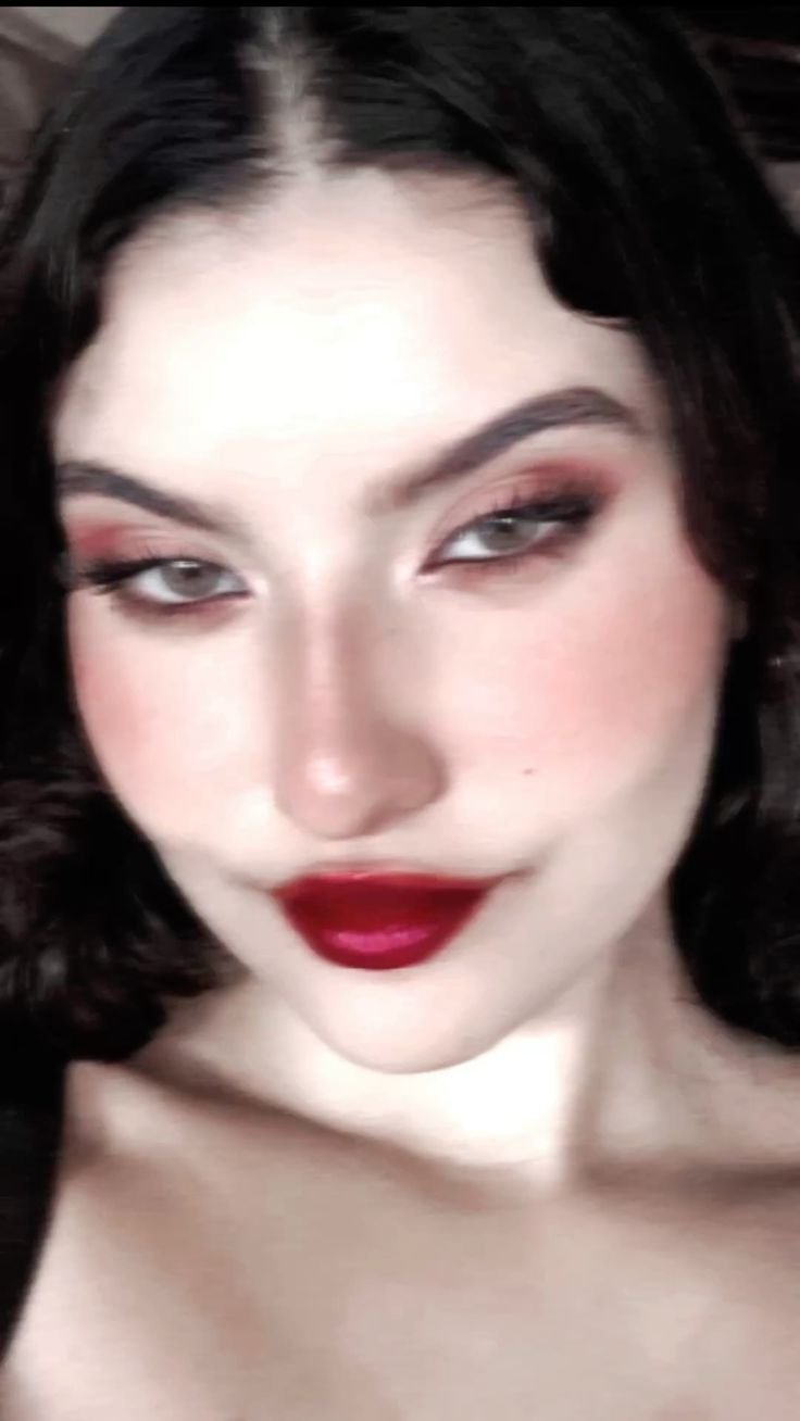 A dark, moody portrait of a woman with red lips and a deep stare, a mysterious pfp.