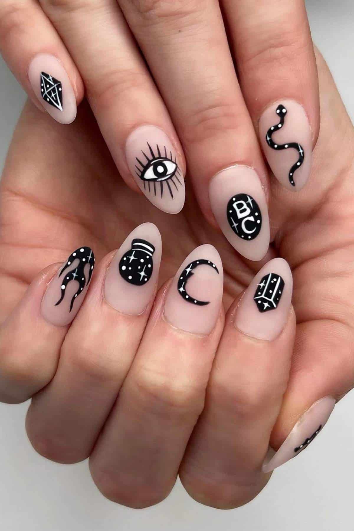 A hand with almond-shaped nails features black and white mystical symbols, including an eye, crescent moon, snake, stars, and geometric designs on a nude background.