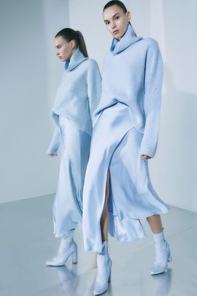 A professional woman wearing an icy blue pantsuit in a modern office setting, showcasing business appropriate styling.