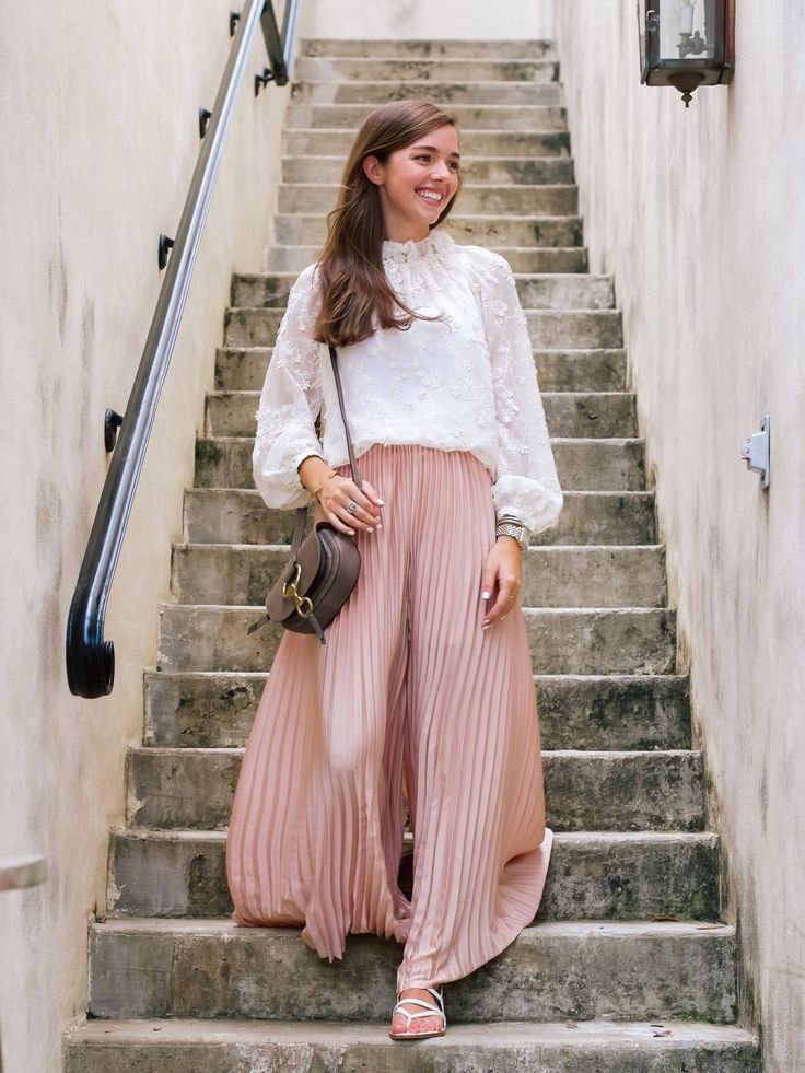 Woman wearing black pleated trousers with a white blouse for a professional work outfit