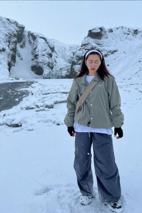 Woman wearing a beanie, sunglasses, and layered cool-toned clothing for an icy style.