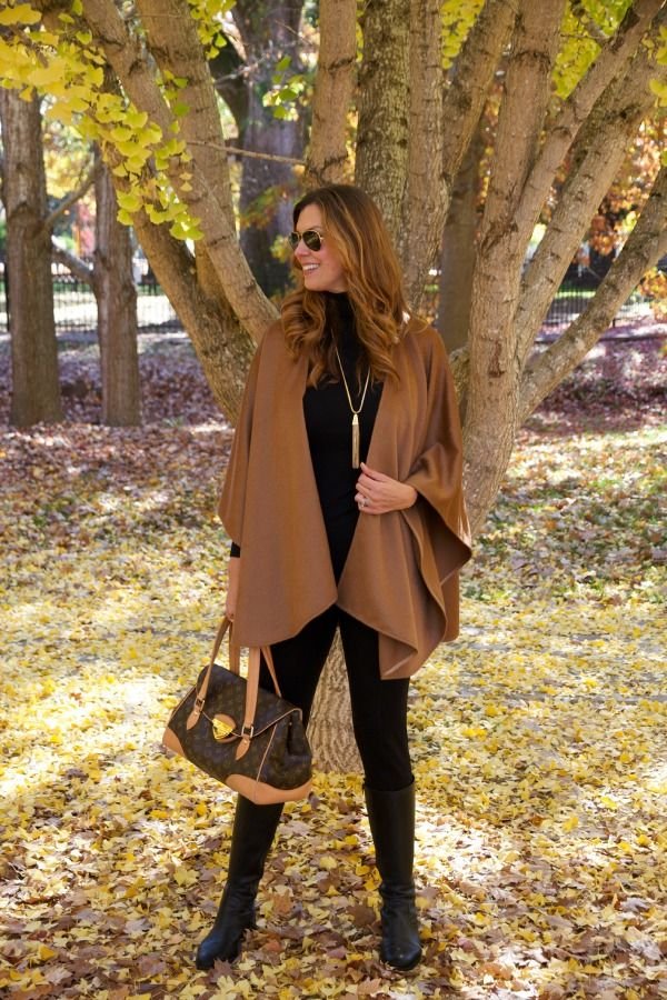 Accessorized cape ensemble featuring a wide belt and statement earrings for definition.